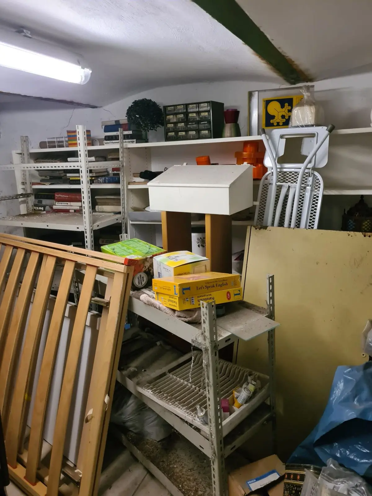 Keller mit vollen Regalen und Hausrat vor einer Entrümpelung