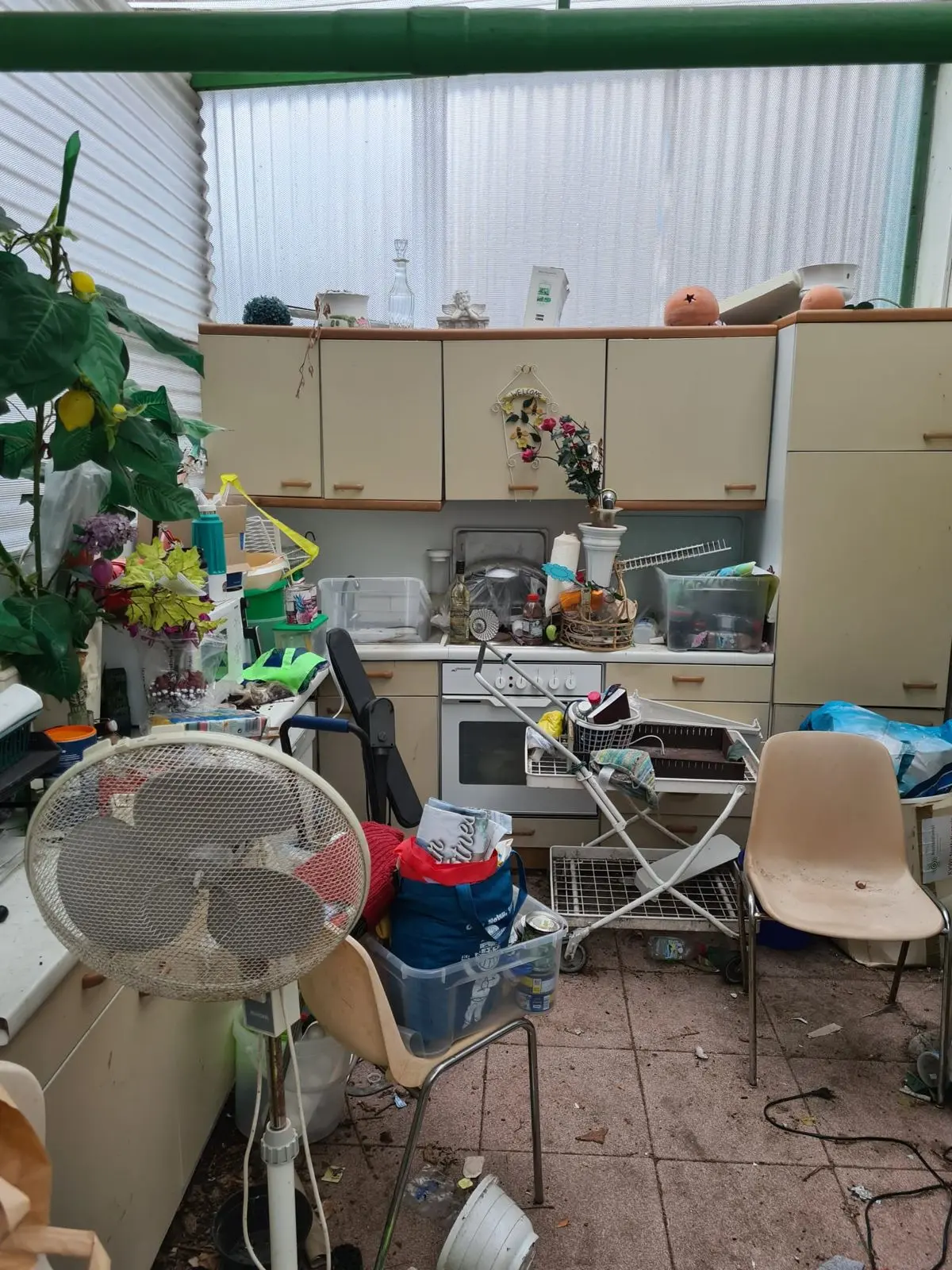 Zugestellter Wintergarten mit Küchenzeile vor einer Entrümpelung durch die Ausmister
